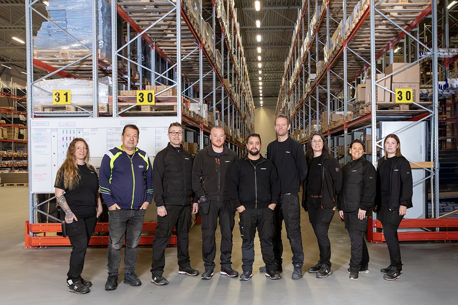Gruppbild på alla anställda ståendes gemensamt i ett lager på logistik27. 